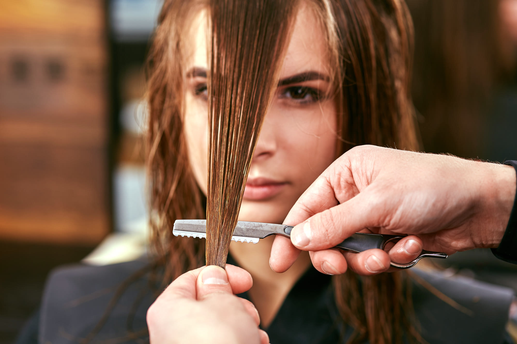 A stylist sectioning and cutting a woman's long hair