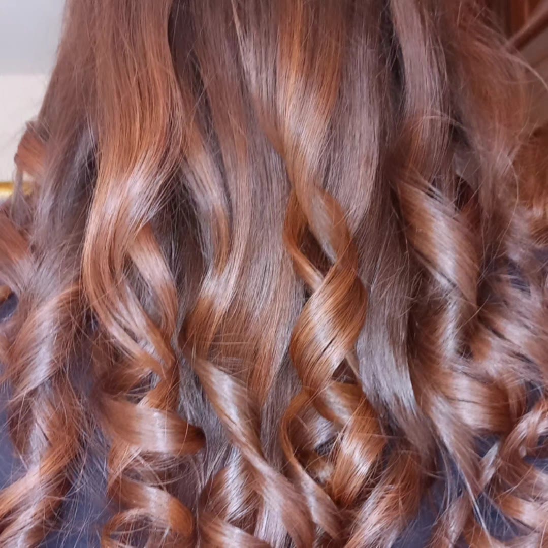 Long copper hair styled into loose spiral curls