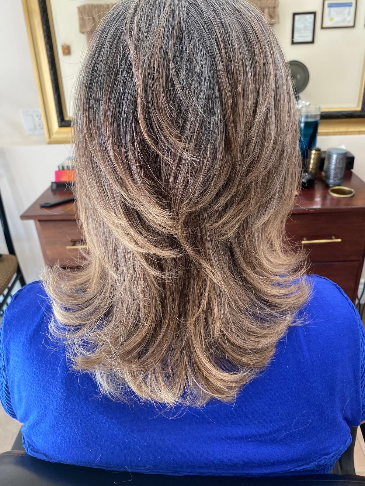 Mid-length layered cut in ash blonde, blow-dried with flicked-out ends