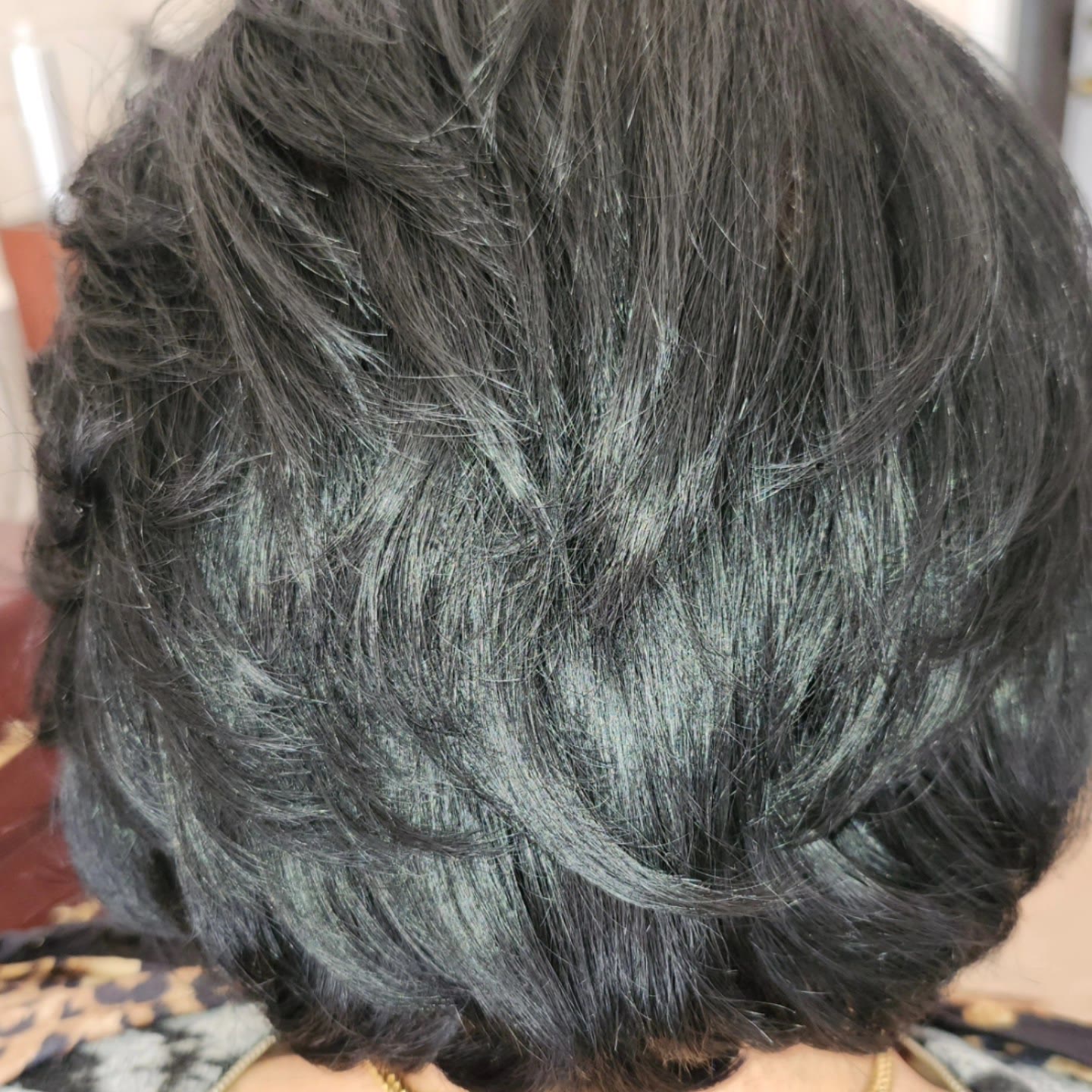 Short layered cut in black hair, with soft feathered layers through the back
